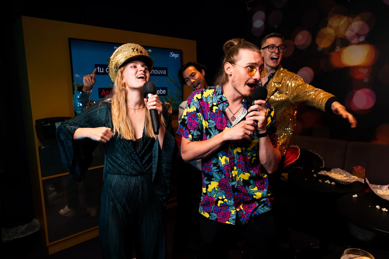 Friends singing together with microphones in a karaoke room