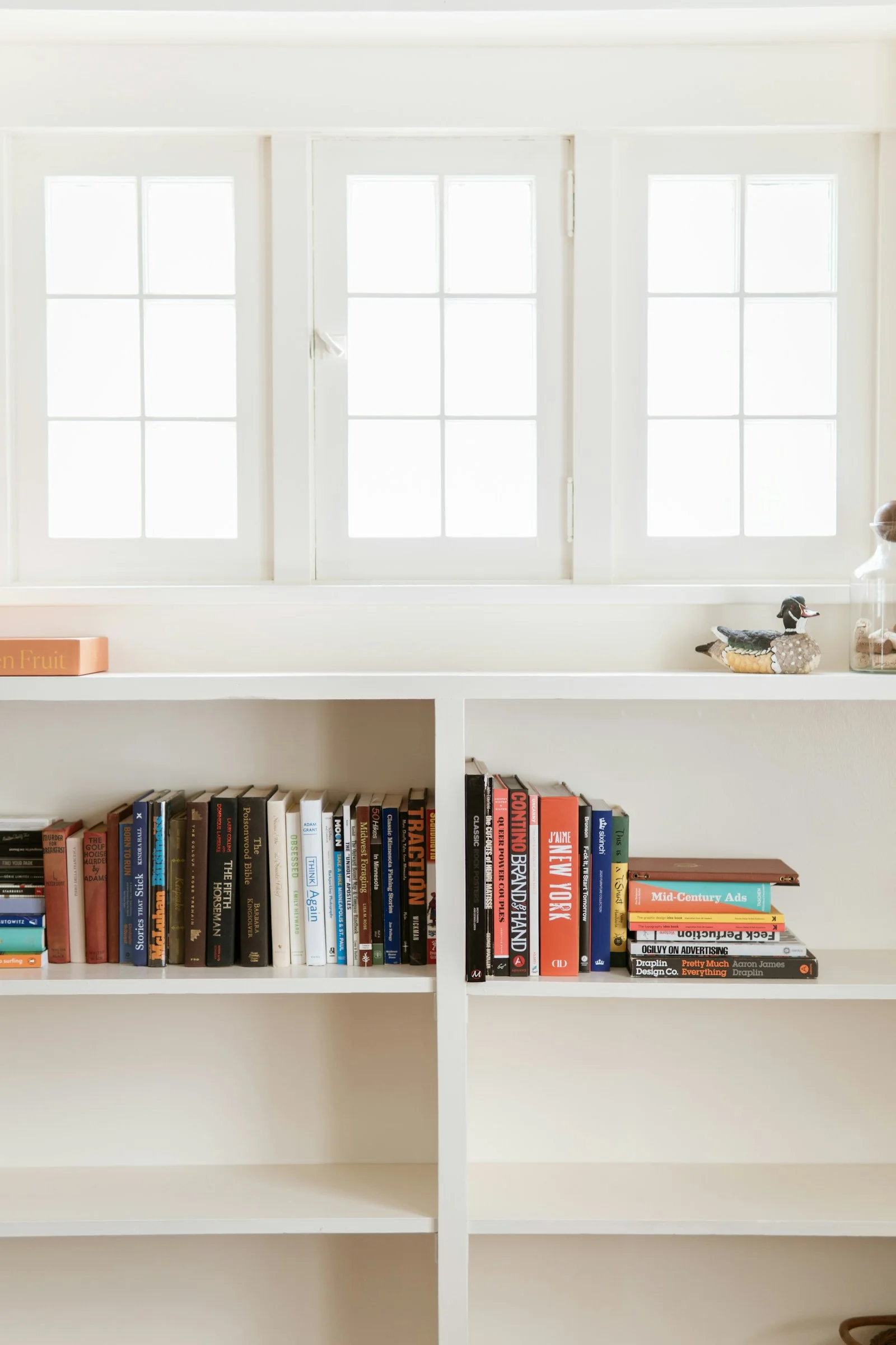 Libros en un estante bajo una ventana luminosa