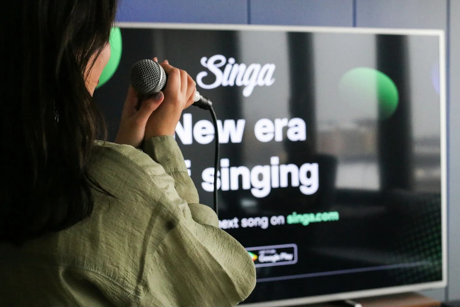 A singer holding a microphone in front of a karaoke screen