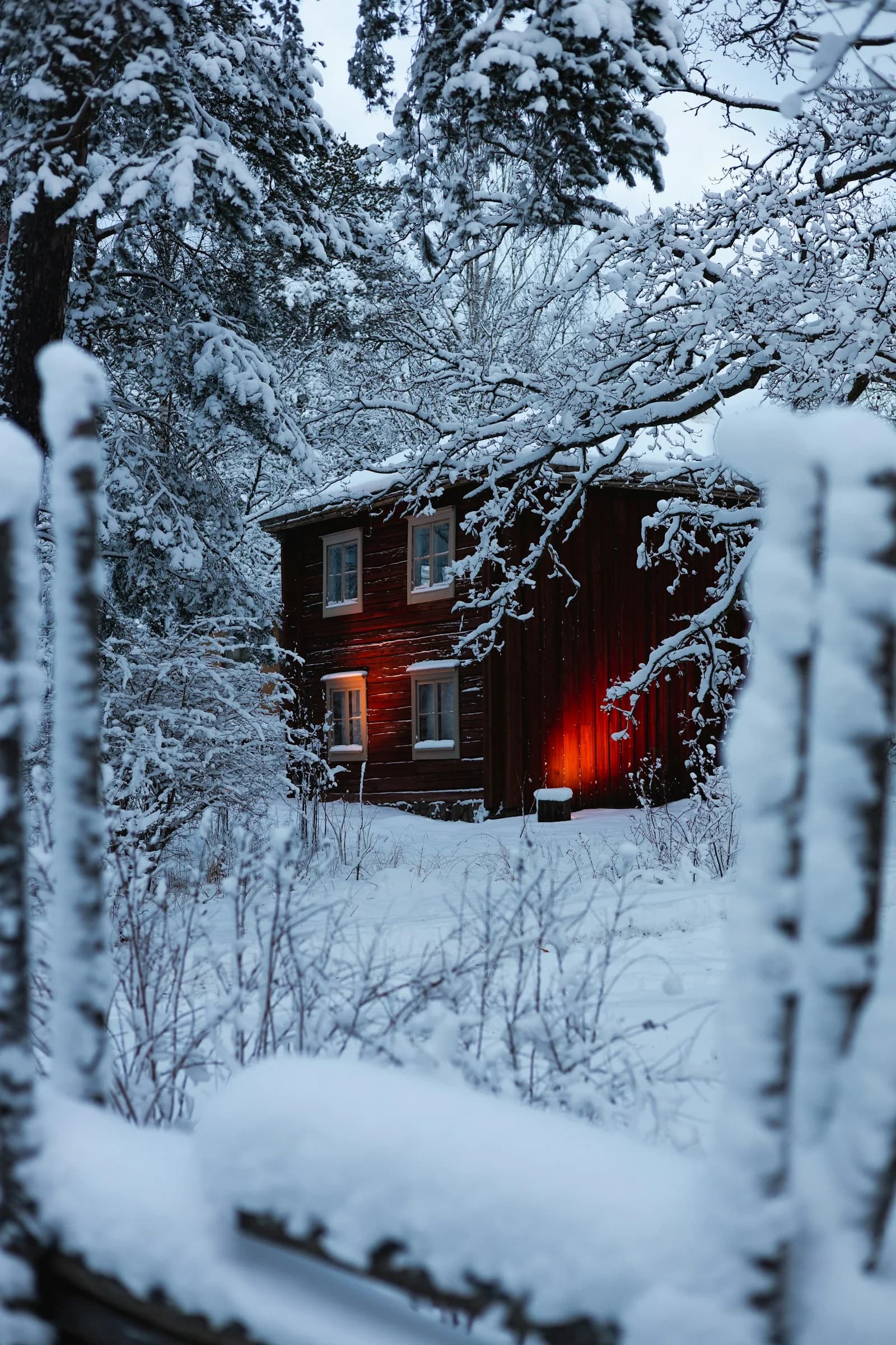 Un chalet en bois et sa fenêtre éclairée au milieu de la neige